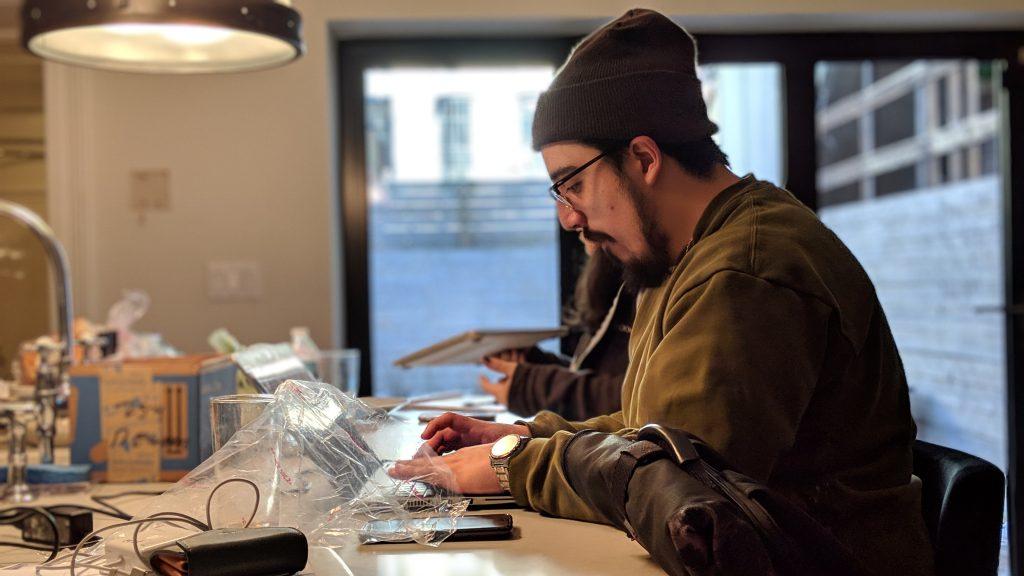 Two Heirloom employees work at the counter in a kitchen in Brooklyn. While the scene looks somewhat hectic, with a plastic bag of food and chargers on the counter, the team is working peacefully, cranking it out.