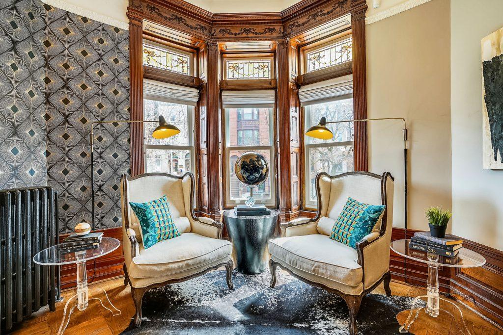 Heirloom homes are like family heirlooms. This photo features two chairs next to one another in front of the windows. Lights frame each chair, and everything has been locally sourced. An antique globe sits between the two chairs on a small table.